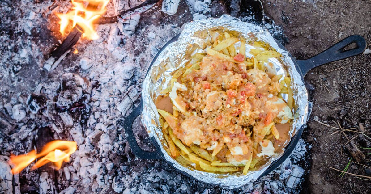 A pan of Nachos being cooked over a Campfire