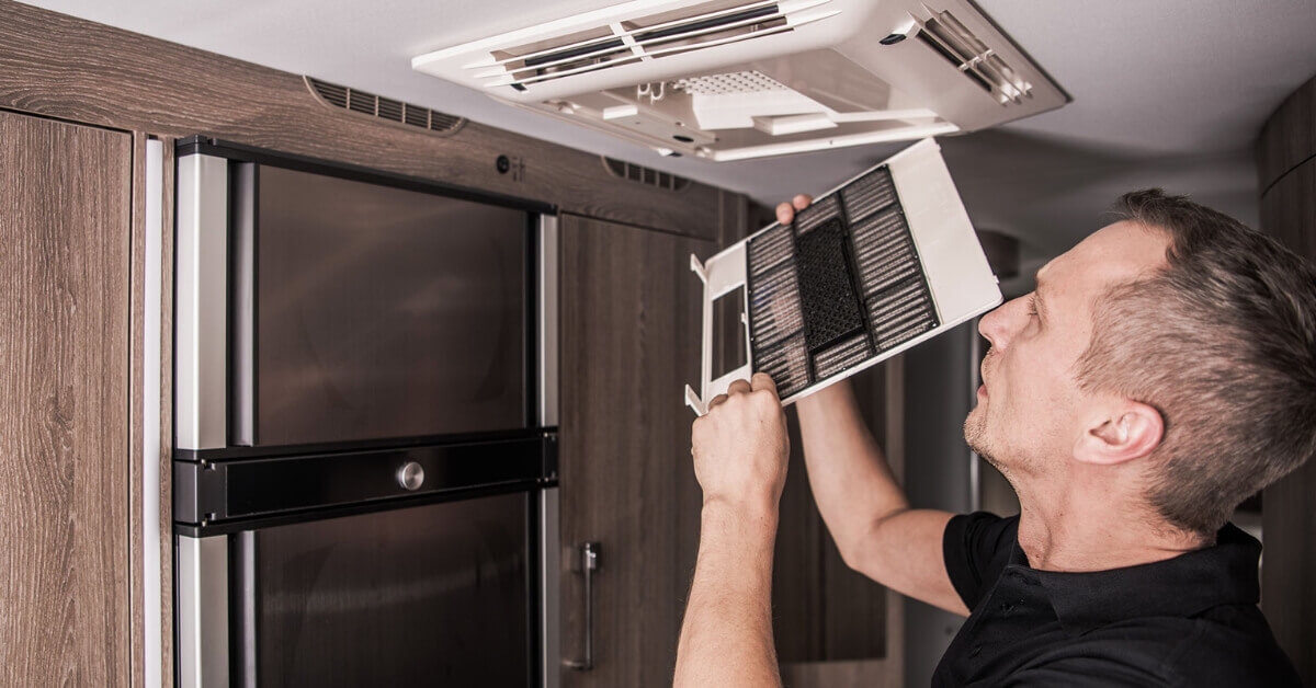 Man replacing an air conditioner filter on his RV 