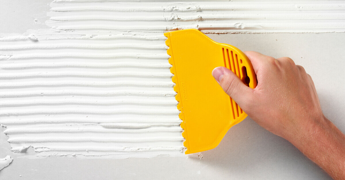 Applying tile adhesive to an RV's wall to install a tile backsplash