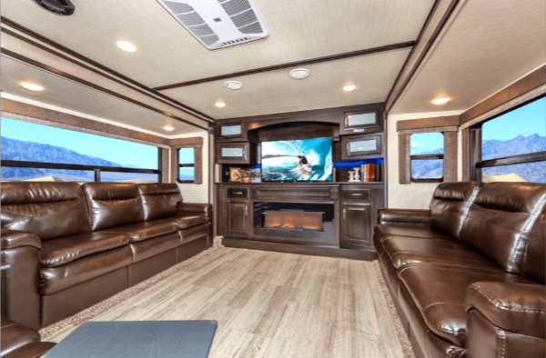 The interior of an RV with leather Chairs and couches and an Entertainment Center