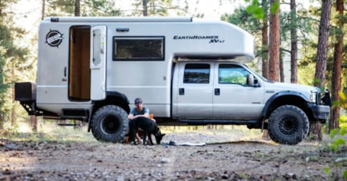A man outside of an RV petting a dog