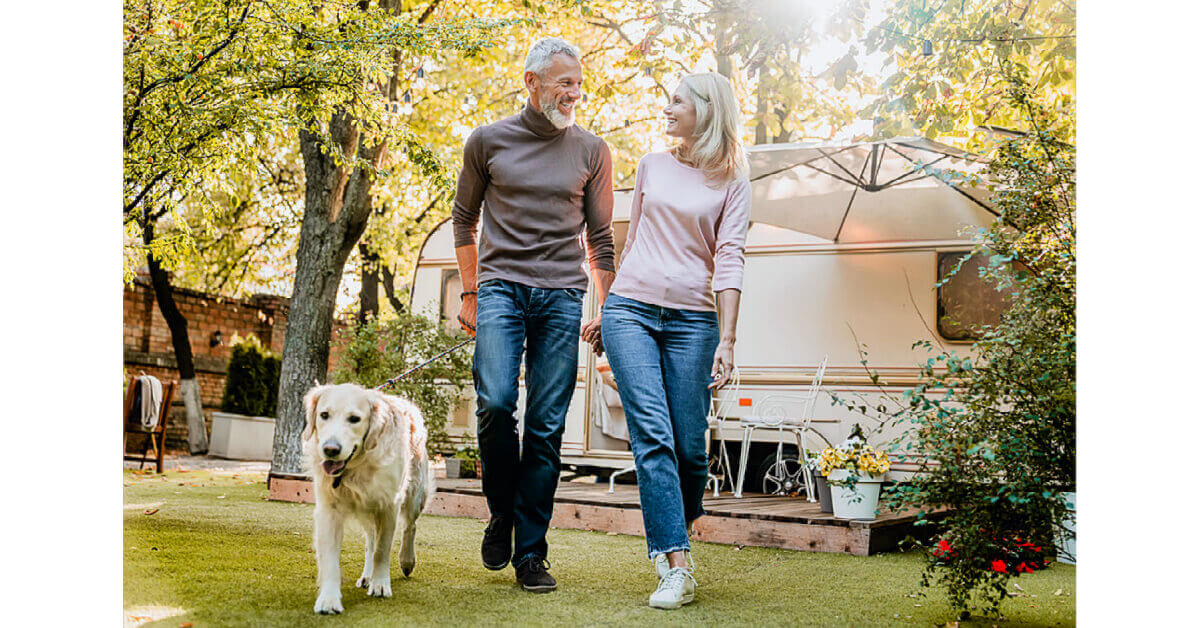 Man and Woman walking a dog at an RV Campground
