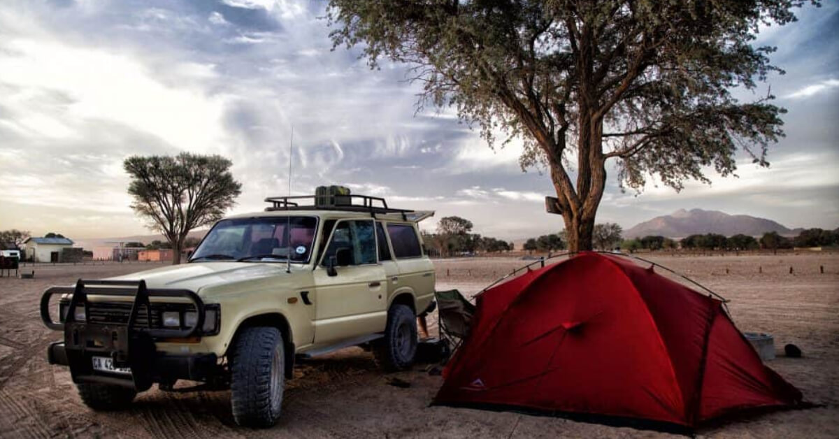 Pickup Truck parked at a campground next to a tent