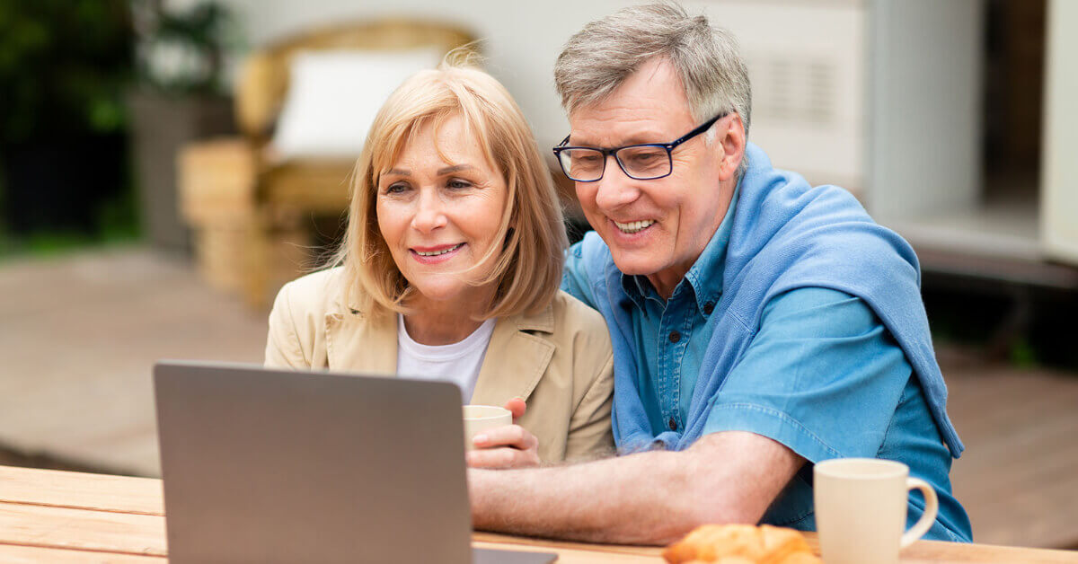 A couple sitting outside of their RVing on their computer