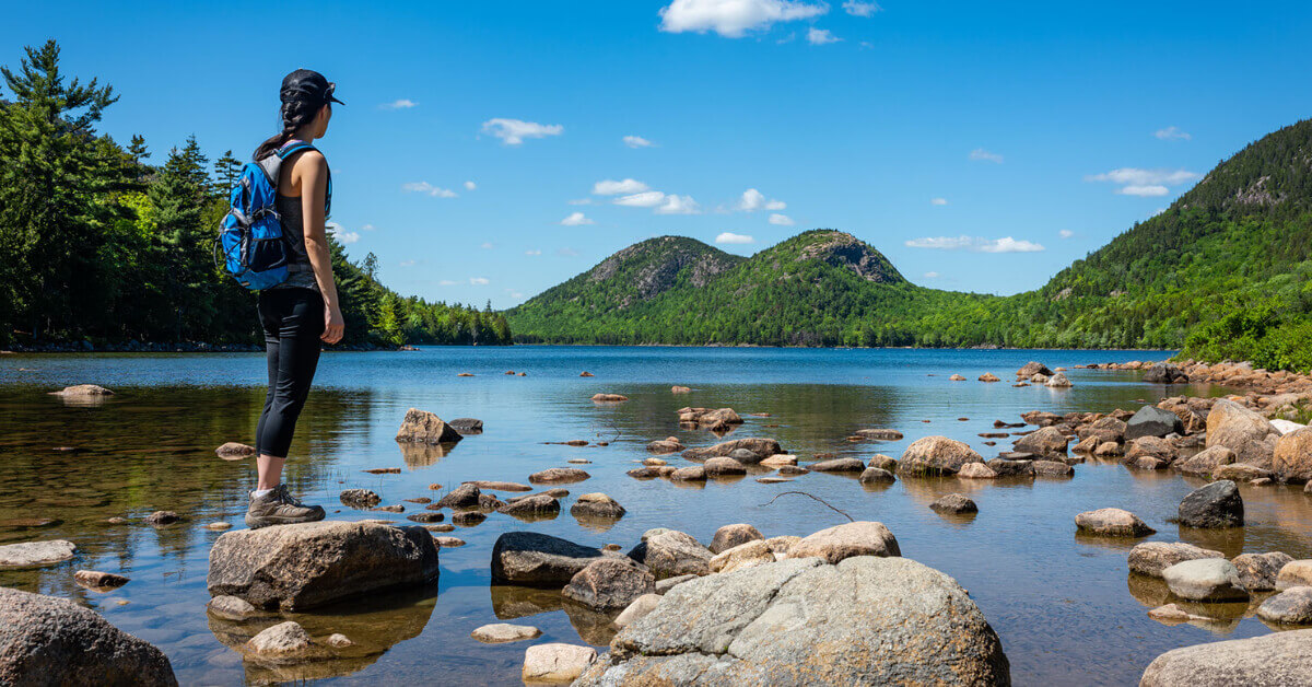 A woman hiking along the rugged coastline of Maine's Acadia National Park 