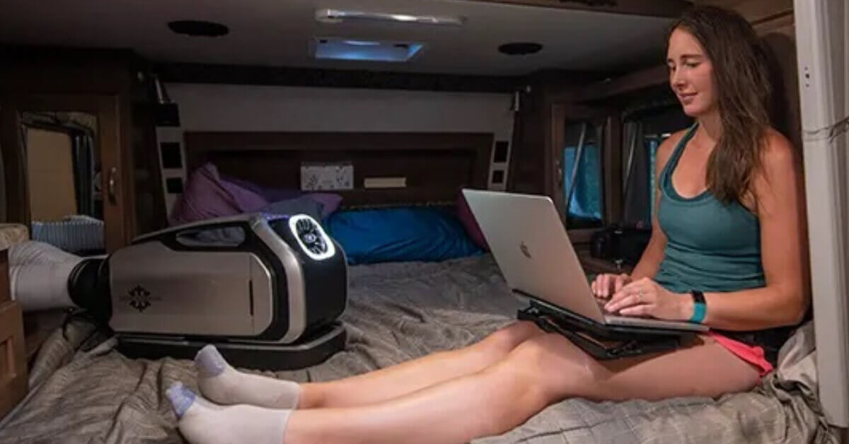 A Women using a computer in her Travel Trailer on a sweltering summer night, but staying cool by using her Zero Breeze Mark 2 Portable AC